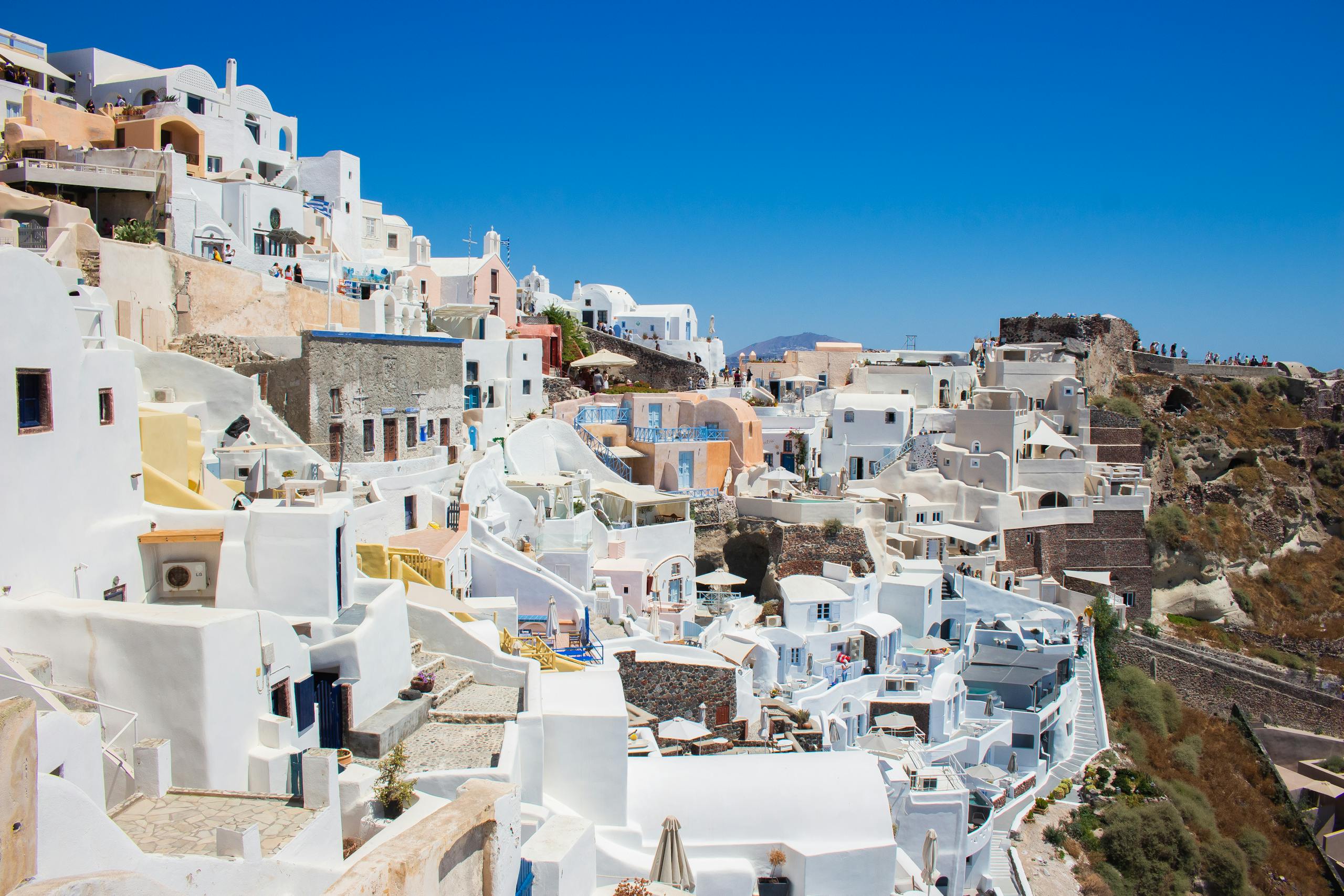 Capture the stunning whitewashed buildings of Santorini, Greece under the bright summer sun.