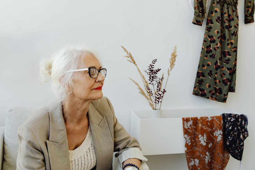 Stylish senior woman with white hair and glasses in a modern indoor setting.