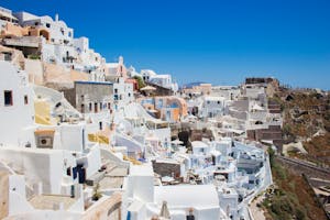 Capture the stunning whitewashed buildings of Santorini, Greece under the bright summer sun.